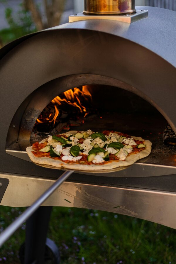 Pizza wird in Outdoor-Pizza Ofen geschoben